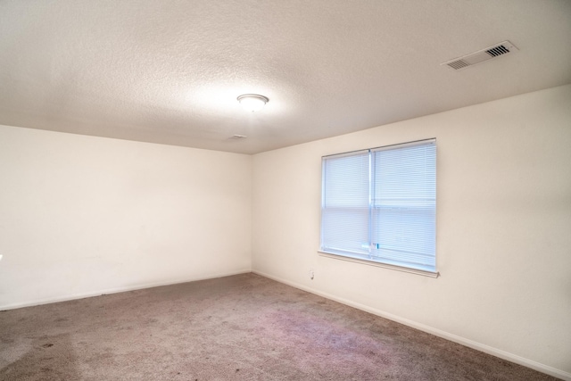 carpeted empty room featuring a textured ceiling