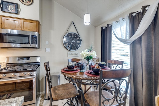 tiled dining area featuring a textured ceiling and vaulted ceiling