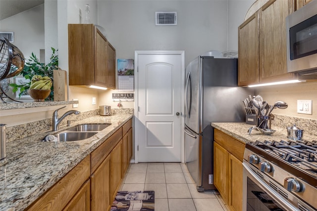 kitchen with light stone counters, sink, light tile patterned floors, and appliances with stainless steel finishes