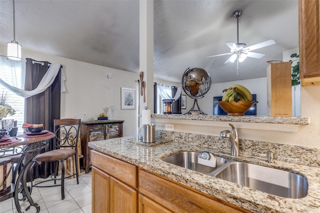 kitchen featuring pendant lighting, sink, ceiling fan, a textured ceiling, and light tile patterned flooring