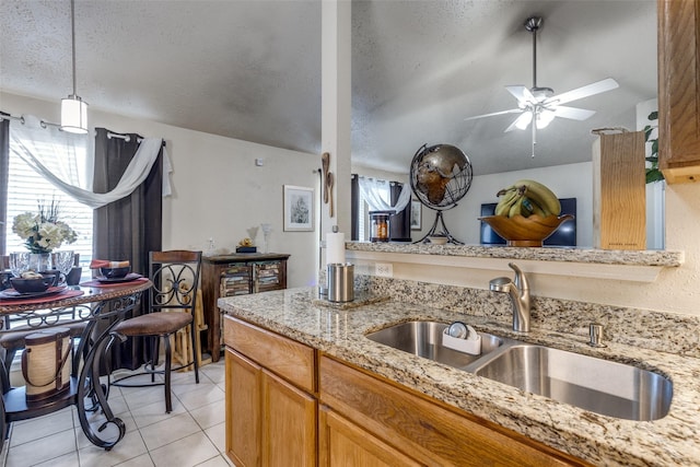 kitchen with ceiling fan, sink, pendant lighting, a textured ceiling, and light tile patterned floors