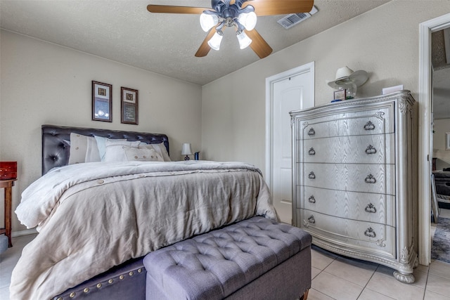 bedroom featuring ceiling fan, light tile patterned flooring, and a textured ceiling