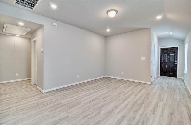 unfurnished room with a textured ceiling, vaulted ceiling, and light hardwood / wood-style flooring