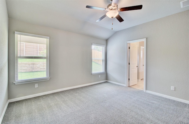 unfurnished room featuring ceiling fan, light colored carpet, a healthy amount of sunlight, and vaulted ceiling