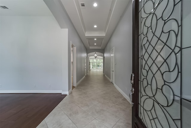 hallway featuring light tile patterned flooring and a raised ceiling