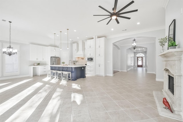 tiled living room with sink, ceiling fan with notable chandelier, and ornamental molding