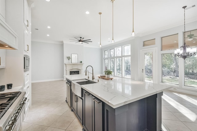 kitchen featuring light stone countertops, sink, a kitchen island with sink, and pendant lighting