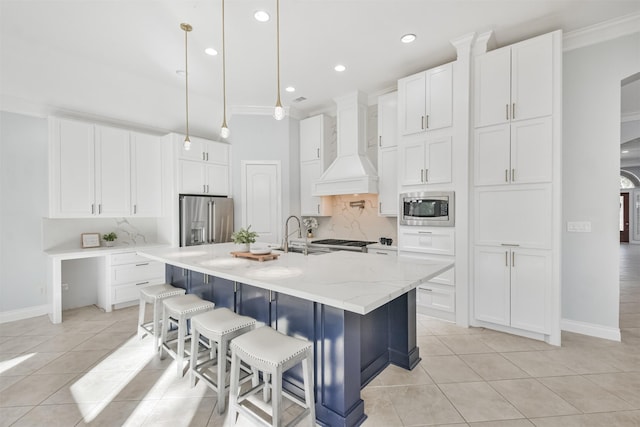 kitchen with pendant lighting, white cabinets, a kitchen island with sink, stainless steel appliances, and custom range hood