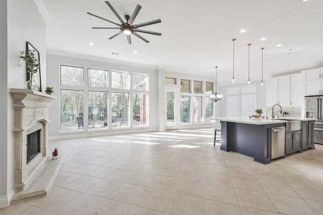 kitchen with sink, a breakfast bar area, stainless steel dishwasher, an island with sink, and pendant lighting