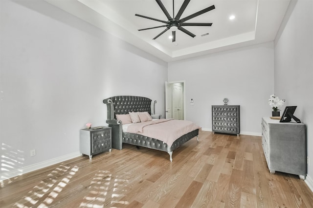 bedroom with hardwood / wood-style flooring, ceiling fan, and a tray ceiling