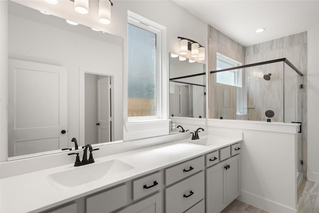 bathroom with vanity, hardwood / wood-style flooring, a wealth of natural light, and a shower with shower door