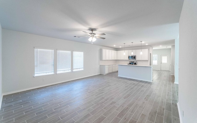 unfurnished living room with ceiling fan and wood-type flooring