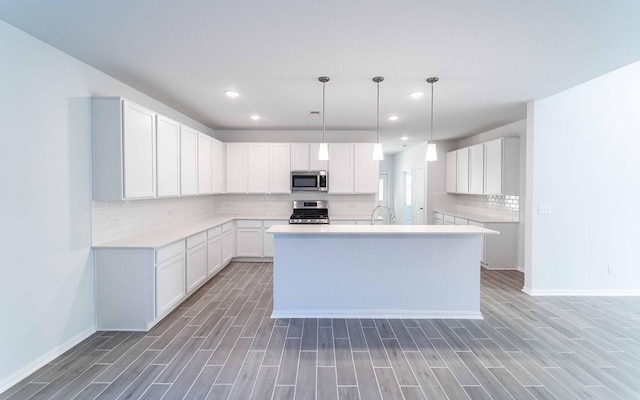 kitchen featuring white cabinets, dark hardwood / wood-style flooring, stainless steel appliances, and a kitchen island with sink