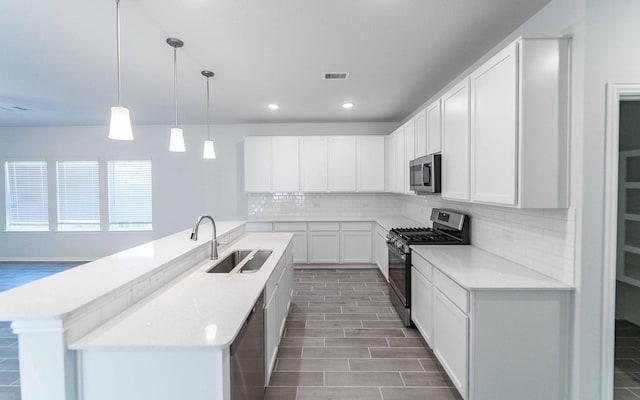 kitchen featuring sink, decorative light fixtures, decorative backsplash, white cabinets, and appliances with stainless steel finishes