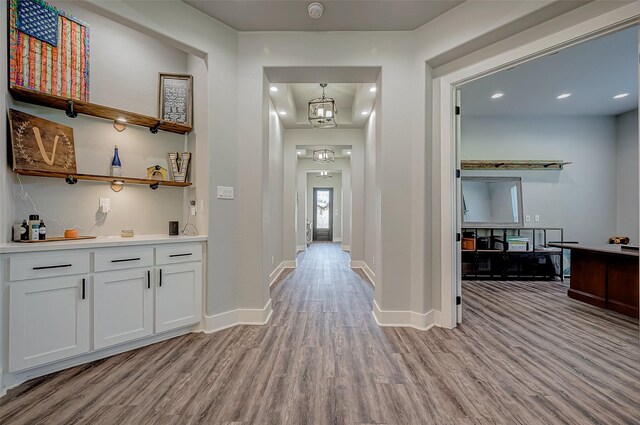 corridor with an inviting chandelier and light hardwood / wood-style flooring