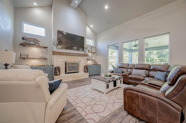 living room featuring a fireplace, light hardwood / wood-style flooring, high vaulted ceiling, and ceiling fan