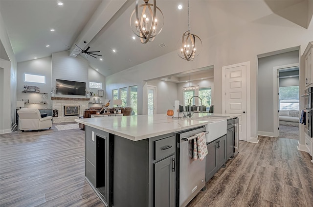 kitchen with a center island with sink, high vaulted ceiling, stainless steel dishwasher, and plenty of natural light