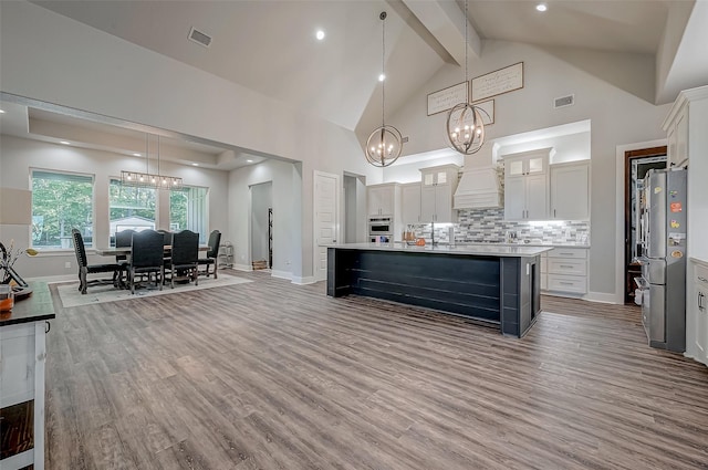 kitchen with hardwood / wood-style flooring, pendant lighting, white cabinetry, and stainless steel refrigerator