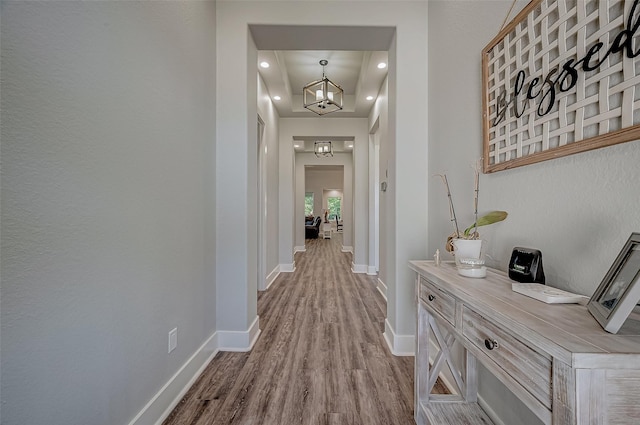 hallway with light hardwood / wood-style floors and a notable chandelier