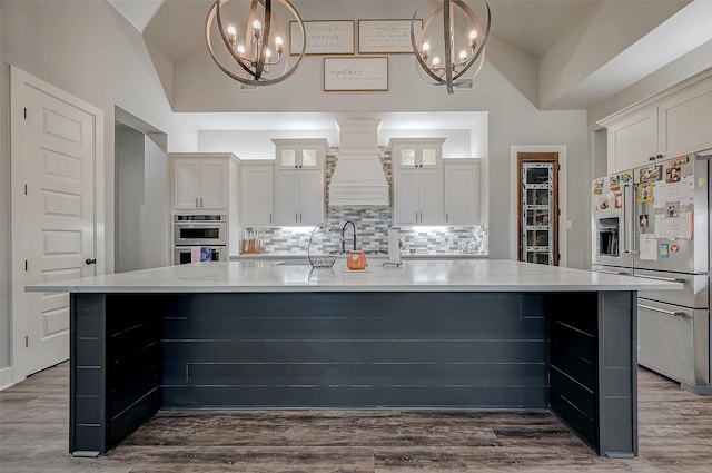 kitchen featuring appliances with stainless steel finishes, decorative light fixtures, and lofted ceiling