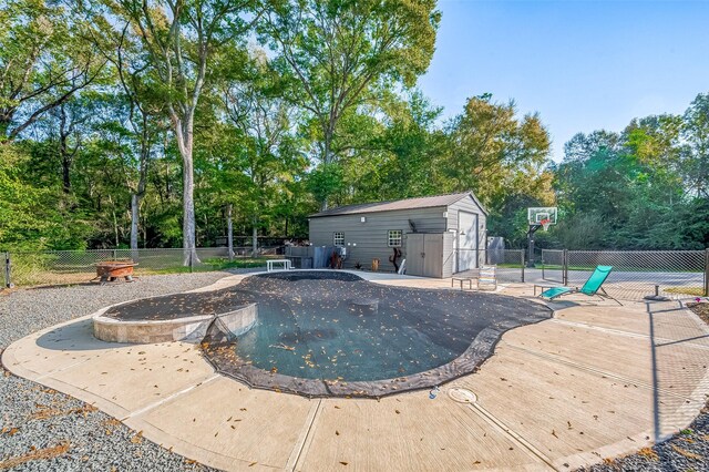 view of swimming pool featuring a storage unit and an outdoor fire pit