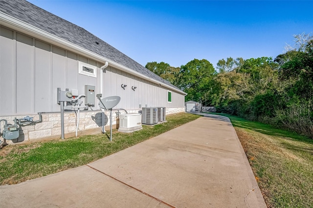 view of side of property featuring a patio, cooling unit, and a lawn