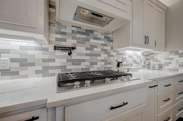 kitchen with decorative backsplash, white cabinets, and ventilation hood