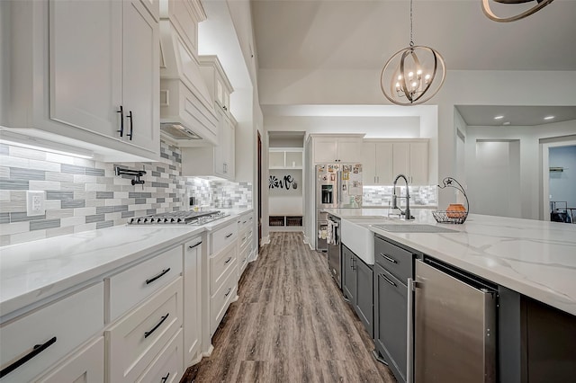 kitchen with stainless steel appliances, white cabinets, hardwood / wood-style floors, a chandelier, and hanging light fixtures