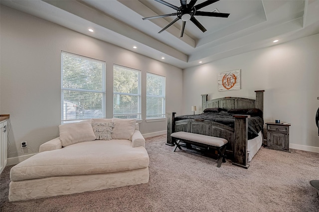 carpeted bedroom featuring ceiling fan and a tray ceiling