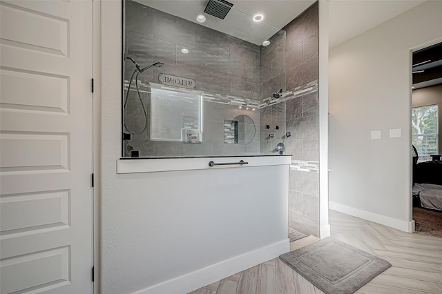 bathroom with tiled shower and wood-type flooring