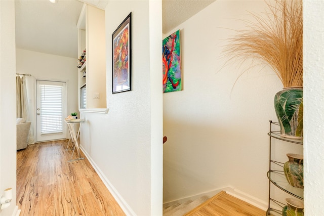 corridor with light hardwood / wood-style floors and a textured ceiling