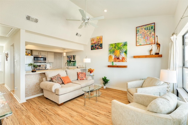 living room with ceiling fan, light wood-type flooring, and high vaulted ceiling