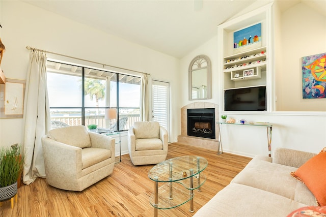 living room with hardwood / wood-style floors, lofted ceiling, and a tile fireplace