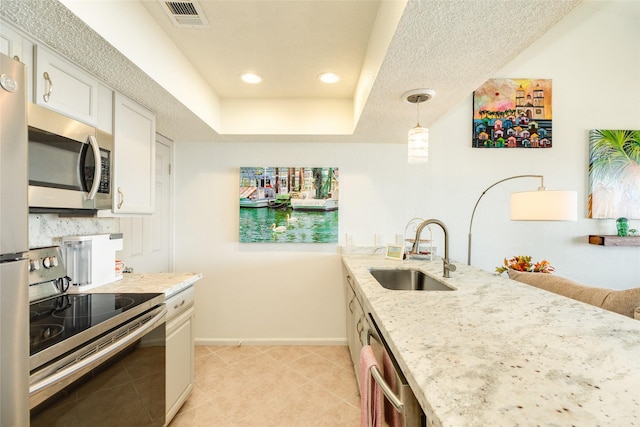 kitchen featuring white cabinetry, sink, hanging light fixtures, light stone counters, and appliances with stainless steel finishes