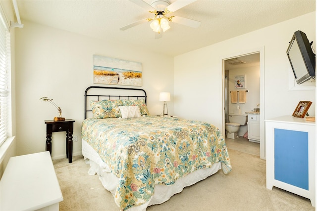 carpeted bedroom featuring a textured ceiling, ceiling fan, multiple windows, and ensuite bath