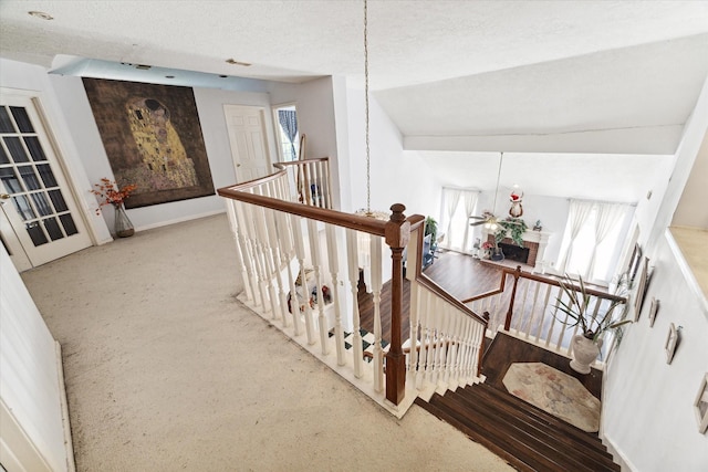 stairs featuring a textured ceiling, plenty of natural light, carpet floors, and vaulted ceiling