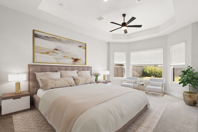 carpeted bedroom with a tray ceiling and ceiling fan