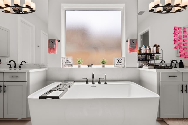 bathroom featuring a tub, vanity, and an inviting chandelier