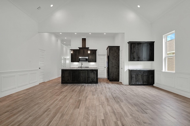 525 Little Spring Ct, Anahuac, TX 77514 - kitchen with stainless steel microwave, high vaulted ceiling, crown molding, light countertops, and a kitchen island with sink