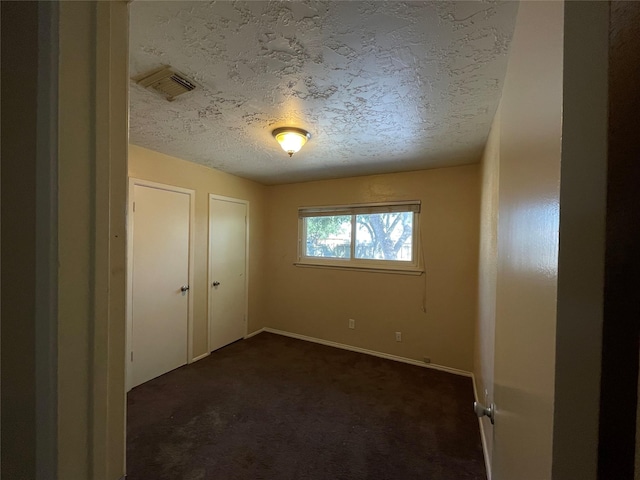 unfurnished bedroom featuring dark colored carpet and a textured ceiling