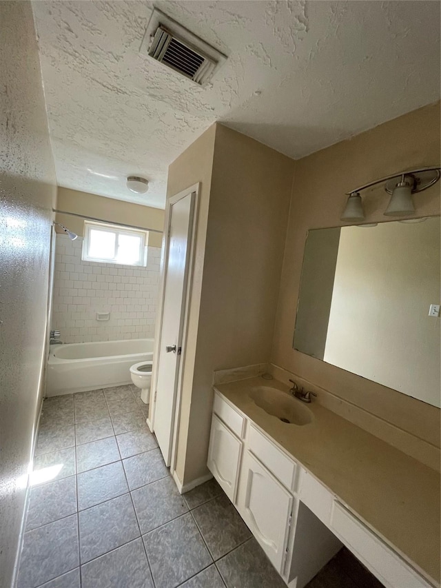 full bathroom with tile patterned floors, toilet, a textured ceiling, vanity, and tiled shower / bath combo