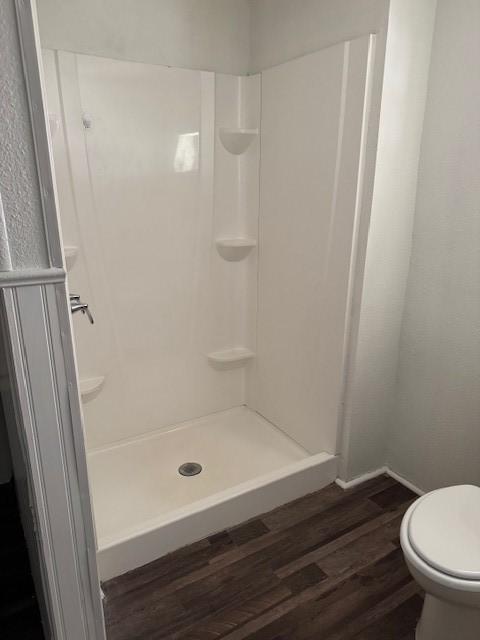 bathroom featuring hardwood / wood-style floors, toilet, and walk in shower