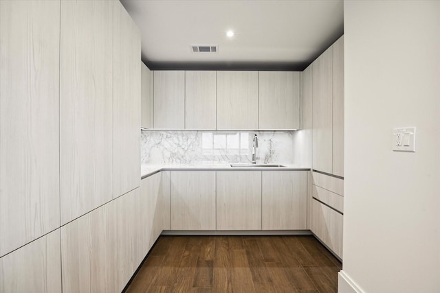 kitchen with light brown cabinetry, backsplash, dark wood-type flooring, and sink