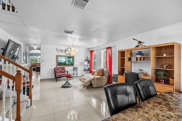 living room with a wealth of natural light, light tile patterned flooring, a textured ceiling, and a notable chandelier