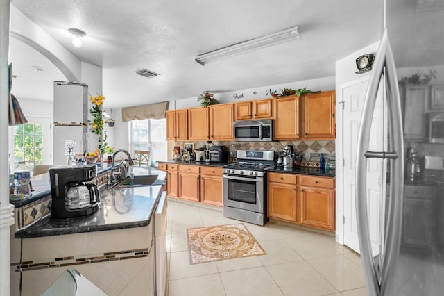 kitchen featuring sink, stainless steel appliances, tasteful backsplash, a textured ceiling, and light tile patterned flooring