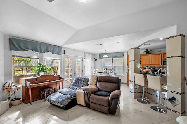 living room featuring french doors, vaulted ceiling, plenty of natural light, and light tile patterned flooring