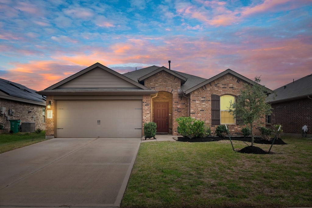 ranch-style home featuring a lawn and a garage