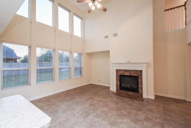 unfurnished living room with a healthy amount of sunlight, a tile fireplace, and a high ceiling