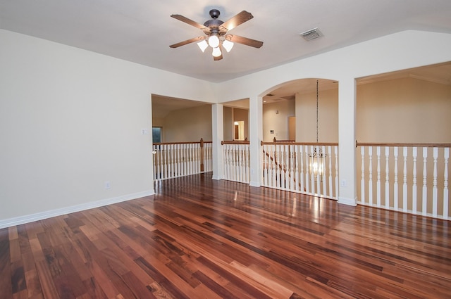 empty room featuring vaulted ceiling, ceiling fan with notable chandelier, and hardwood / wood-style flooring