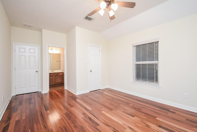 unfurnished bedroom featuring ceiling fan, dark hardwood / wood-style flooring, ensuite bathroom, lofted ceiling, and a closet